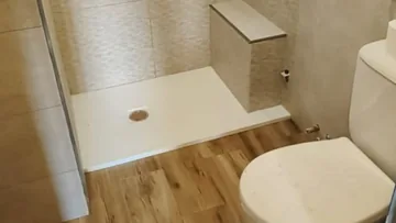 Baño reformado con plato de ducha, sanitario e instalación terminada